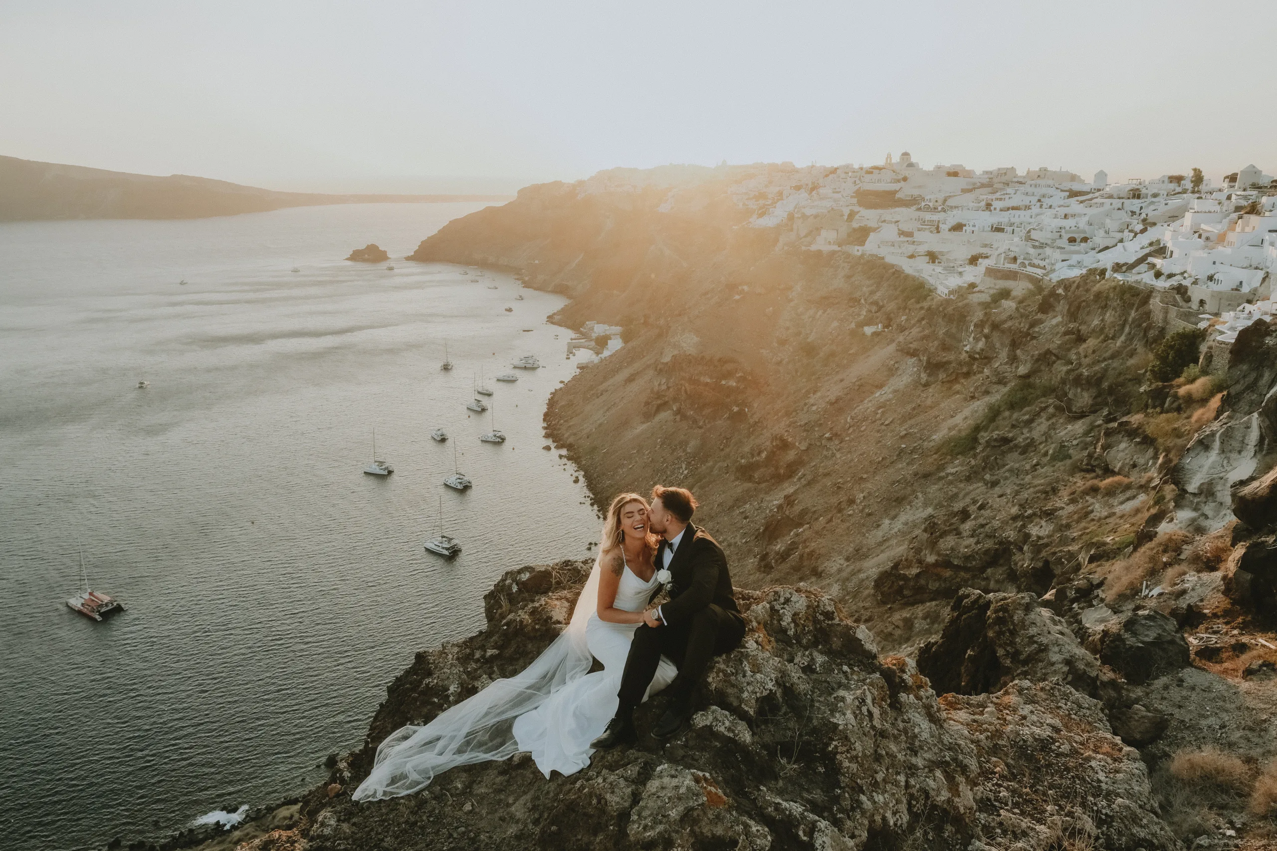 Bride and groom on the caldera cliff at sunset in Santorini