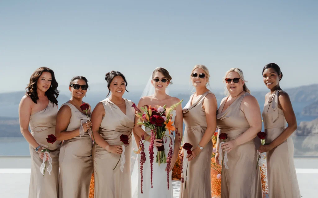 Kerry & Ayden wedding at Santorini Gem — bridesmaids in champagne dresses by the caldera