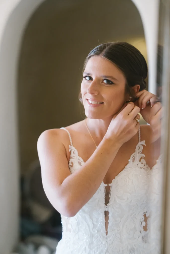 Andrea & Jordan wedding at Love Cave Venue, Santorini — the bride fastening her earrings