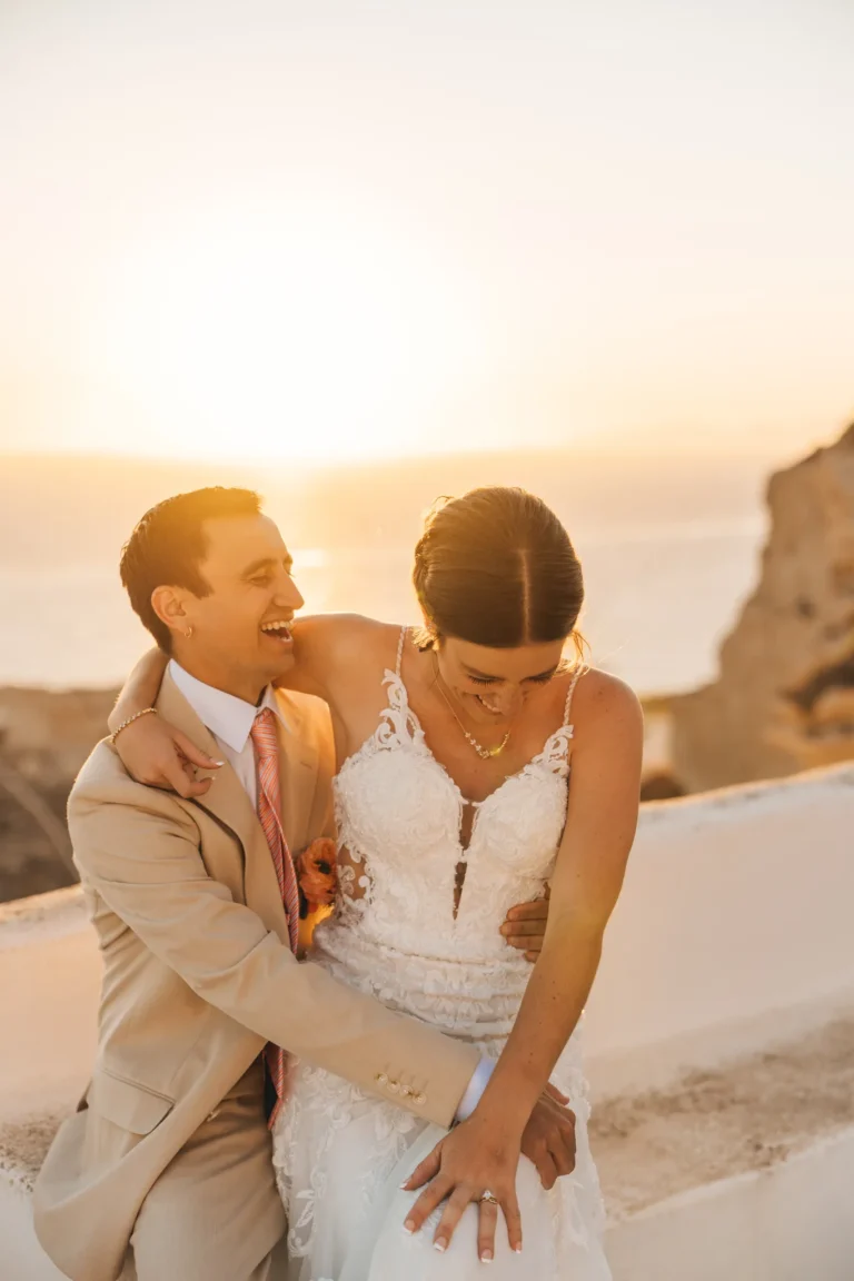 Andrea & Jordan wedding at Love Cave Venue, Santorini — the groom kissing his bride’s shoulder at sunset