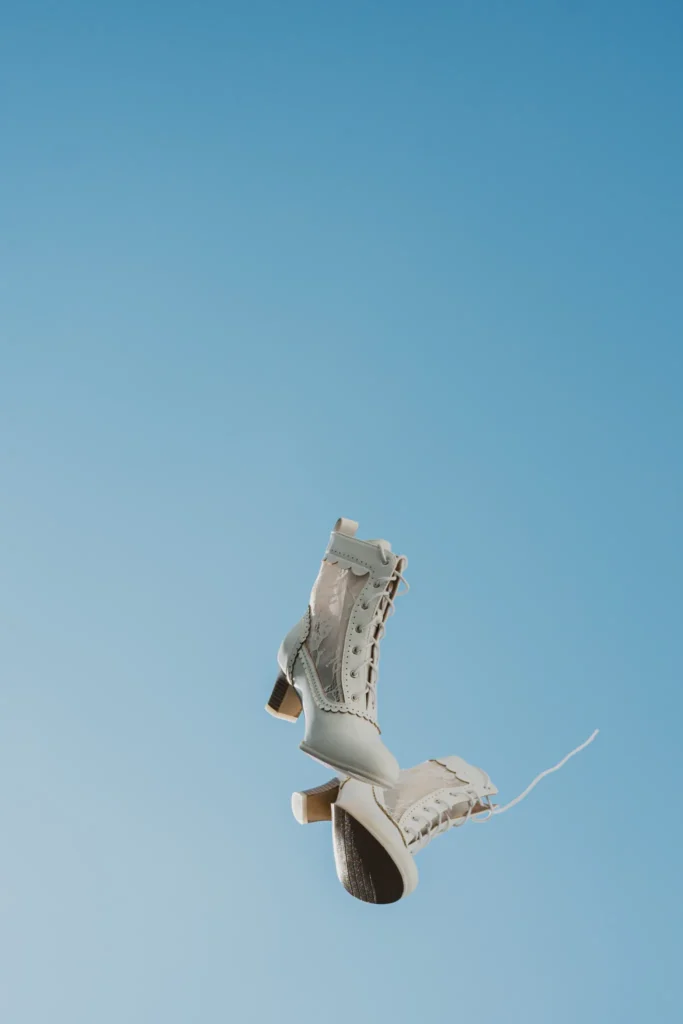Angela & David wedding aboard a traditional Greek boat, Santorini — the bride’s lace-up boots against the sky