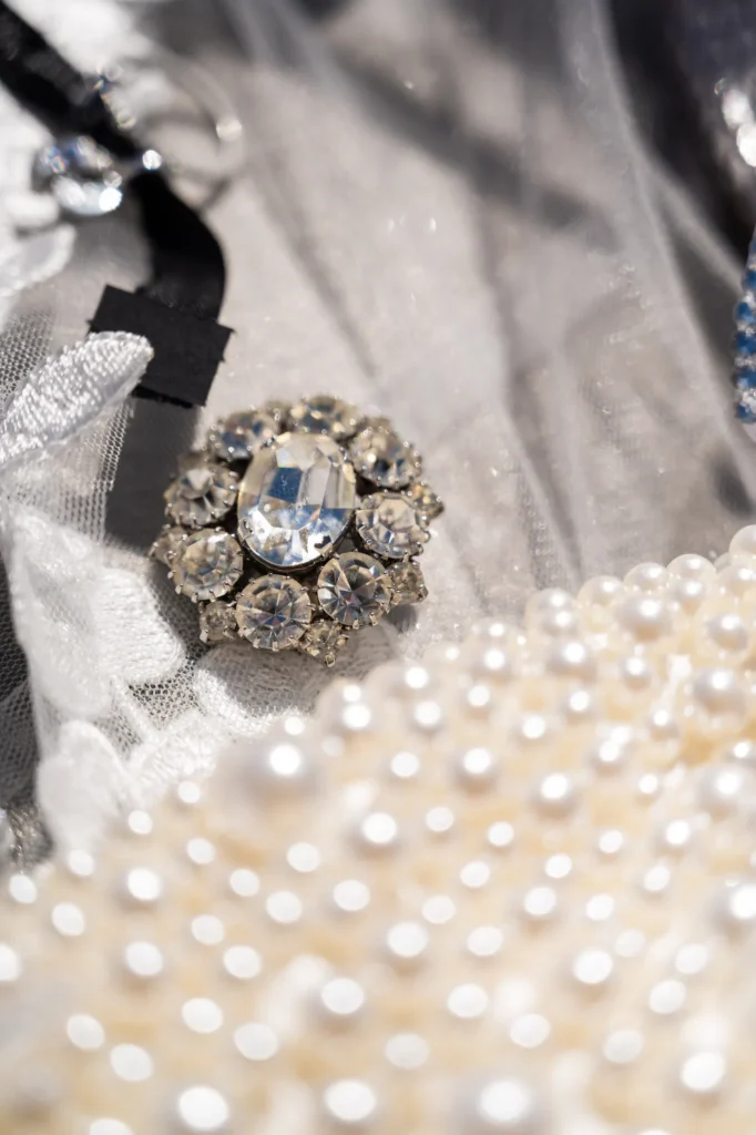 Crystal & Gabriel wedding at Love Cave Venue, Santorini — a jewelled brooch among the pearls