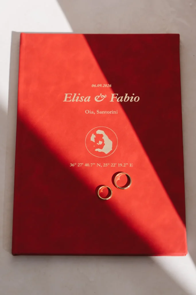 Elisa & Fabio wedding at Love Cave Venue, Santorini — the red vow book with their names in gold