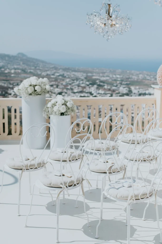 Hazel & Soltan wedding at Madame Sousou, Santorini — white chairs and florals looking out over the island