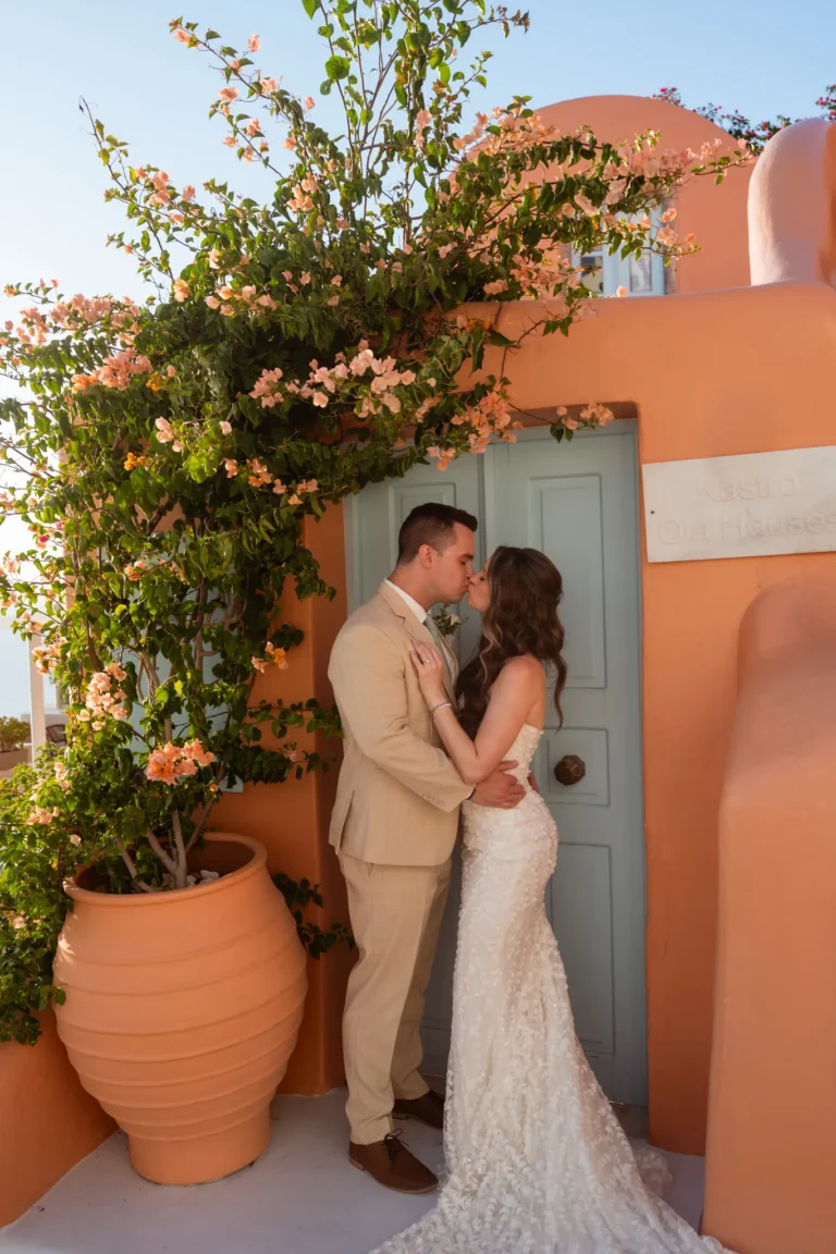 Holly & Taylor wedding at Love Cave Venue, Santorini — a kiss by a blue door in Oia